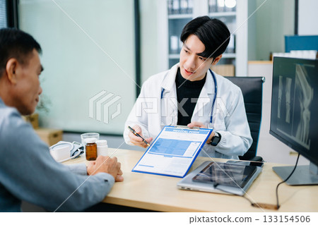 Doctor consulting patient using medical form and X-ray scan in clinic. Ideal for themes of diagnosis, health insurance, communication Doctor consulting patient using medical form and X-ray scan in clinic. Ideal for themes of diagnosis, health insurance, communication 133154506