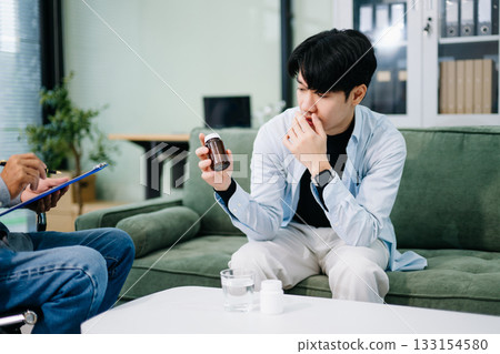 Asian man talks to psychiatrist about mental health issues. Concept of therapy, stress, anxiety, support, and emotional wellness. Asian man talks to psychiatrist about mental health issues. Concept of therapy, stress, anxiety, support, and emotional wellness. 133154580