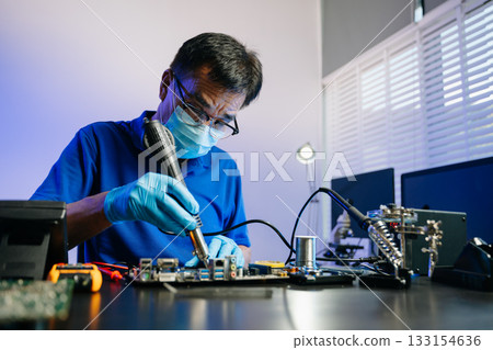 Skilled technician in lab coat and gloves recovers data from hard disk. 133154636