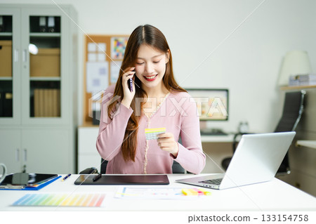 Asian designer using digital pen and laptop in a creative office, showcasing professional work, innovation, 133154758