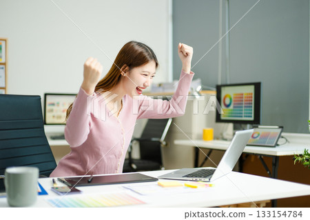 woman celebrates success while working on a tablet in a modern creative office, capturing achievement woman celebrates success while working on a tablet in a modern creative office, capturing achievement 133154784