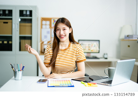 Smiling young professional confidently presents creative ideas in a modern office, showcasing innovation 133154789