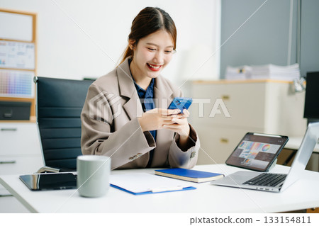 Asian business woman typing laptop and tablet Placed at the table at the office Asian business woman typing laptop and tablet Placed at the table at the office 133154811
