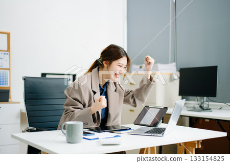 Asian business woman are delighted and happy with the work they do on their tablet, laptop and taking notes Asian business woman are delighted and happy with the work they do on their tablet, laptop and taking notes 133154825
