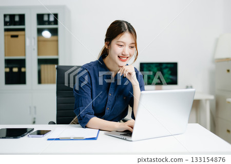 Confident businesswoman working on laptop in a modern office. Elegant and focused, perfect for themes of remote work 133154876