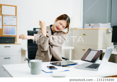 Overworked young Asian businesswoman office worker suffering from neck pain after had a long day at her office desk. 133154890