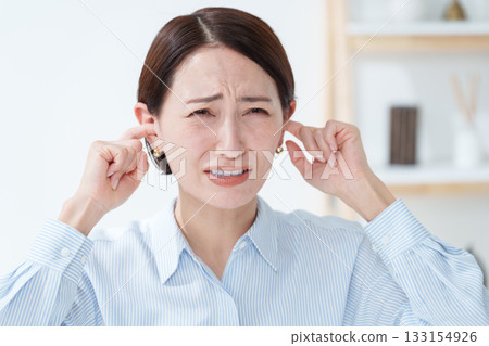 Woman covering her ears from the noise Woman covering her ears from the noise 133154926