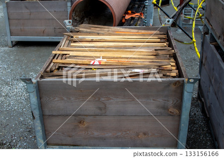 Wooden planks stored in a metal container at a construction site during daylight 133156166