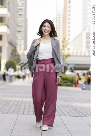 A businesswoman in her 30s walking through an office district 133157186