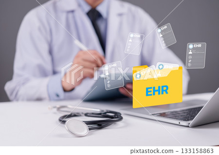Doctor using digital tablet with EHR folder icon and medical records floating above laptop, representing electronic health records and modern healthcare technology concept. 133158863