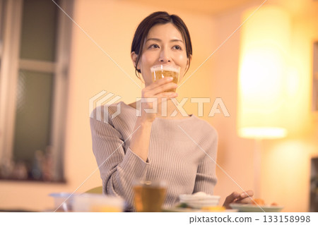 中年婦女一邊吃晚餐一邊喝啤酒 中年婦女一邊吃晚餐一邊喝啤酒 133158998