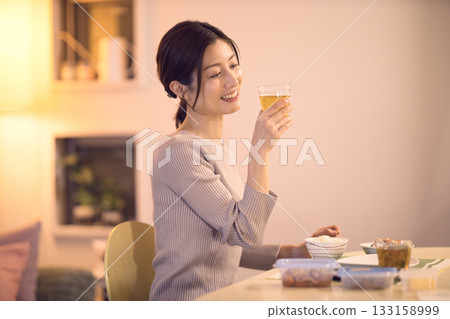 中年婦女一邊吃晚餐一邊喝啤酒 中年婦女一邊吃晚餐一邊喝啤酒 133158999