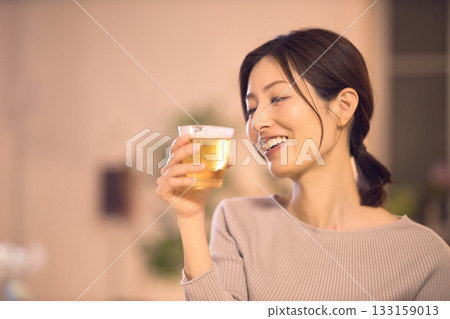 中年婦女一邊吃晚餐一邊喝啤酒 中年婦女一邊吃晚餐一邊喝啤酒 133159013