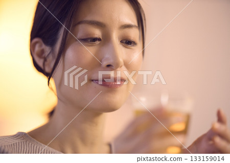 Middle-aged woman eating dinner while drinking beer Middle-aged woman eating dinner while drinking beer 133159014