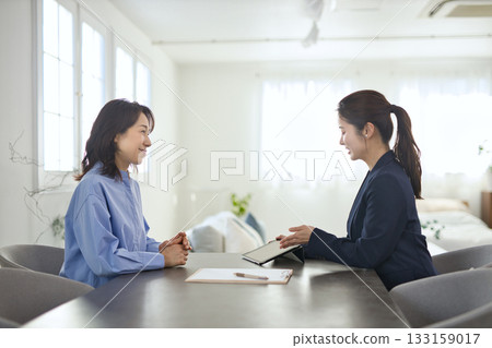 一位年輕女商人向一位中年婦女解釋 133159017