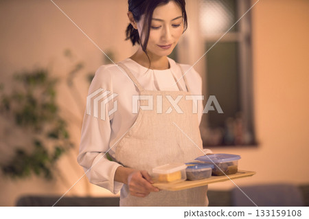 Middle-aged woman carrying dinner to the table 133159108