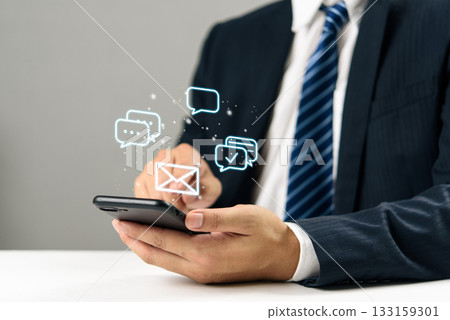 Businessman hand holding smartphone with digital chat and email icons, communication online messaging, social media, mobile marketing, and modern customer engagement technology. 133159301