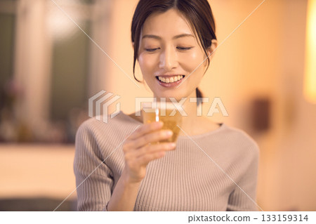 A middle-aged woman having dinner while drinking beer 133159314