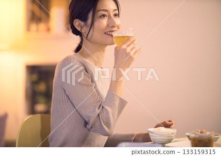 Middle-aged woman eating dinner while drinking beer 133159315