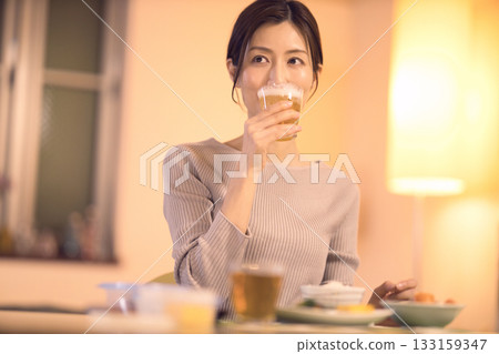 中年婦女一邊吃晚餐一邊喝啤酒 中年婦女一邊吃晚餐一邊喝啤酒 133159347
