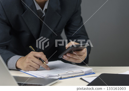 Close-up of hands managing paperwork and a mobile phone, representing financial transactions, legal agreements, or modern business operations. 133161003
