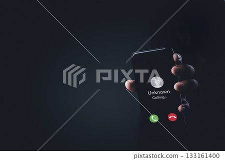 Hand holding mobile phone with unknown caller notification, concept of telephone fraud, call blocking, digital security, unwanted calls, anonymous communication, phishing attempt. 133161400