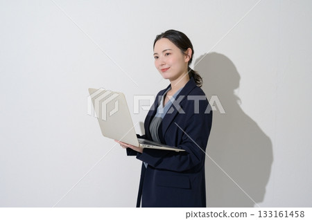 一位日本女性在白色背景下拿著筆記型電腦。 133161458