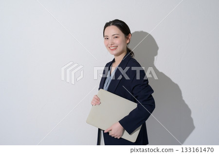 一位日本女性在白色背景下拿著筆記型電腦。 一位日本女性在白色背景下拿著筆記型電腦。 133161470