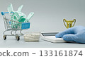 Mini shopping cart filled with dental impression trays beside a jaw model, calculator, and trophy, symbolizing cost, quality, and dental excellence. 133161874