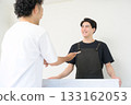 A man wearing an apron serving customers at the reception desk 133162053