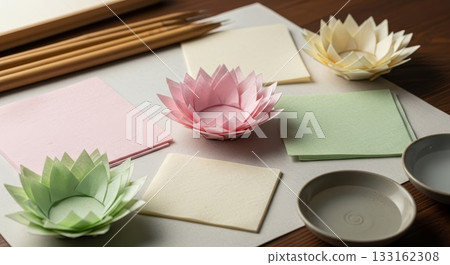 Handcrafted paper lotus flowers in pink green yellow colors with notebooks and ceramic bowls on wooden desk for origami crafting workspace 133162308