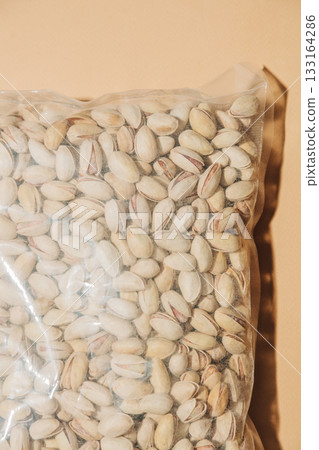 Salted pistachios in plastic bag green background Salted pistachios in plastic bag green background 133164286