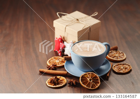 Hot chocolate in blue cup with organic decorations and chrismas gift on walnut table Hot chocolate in blue cup with organic decorations and chrismas gift on walnut table 133164587