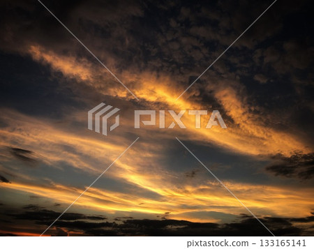 橘色的夕陽籠罩著天空，雲彩繚繞。 133165141