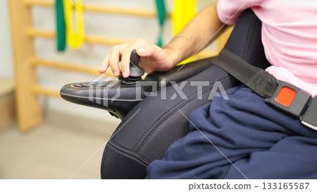 Person operating power wheelchair joystick for increased mobility 133165587