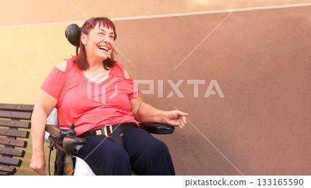 Smiling woman with physical disability in electric wheelchair Smiling woman with physical disability in electric wheelchair 133165590