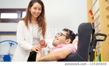 Physiotherapist assisting man with physical disability in rehabilitation exercise 133165634