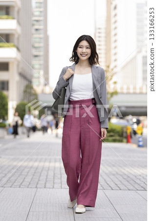 A businesswoman in her 30s walking through an office district A businesswoman in her 30s walking through an office district 133166253