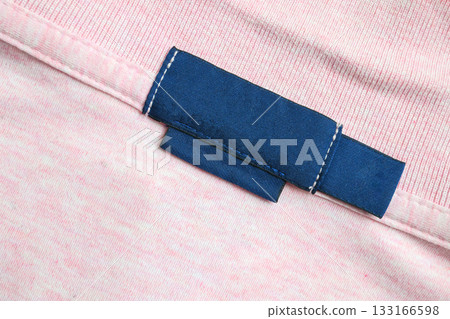 Blank blue laundry care clothes label on pink shirt fabric texture background 133166598