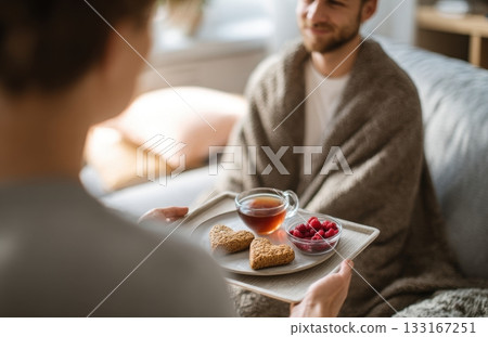 Caring partner bringing heart shaped breakfast to sick man 133167251