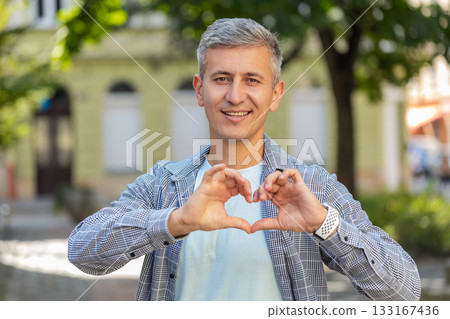 Caucasian man makes symbol of love, showing heart sign express romantic feelings on city street Caucasian man makes symbol of love, showing heart sign express romantic feelings on city street 133167436