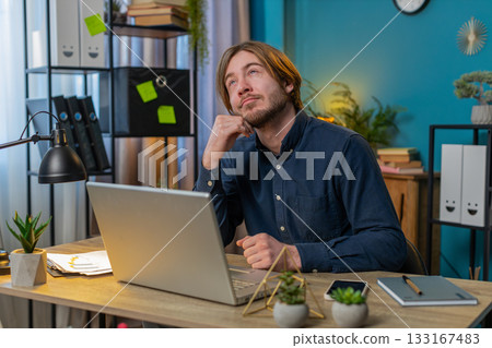 Thoughtful concerned businessman working on laptop computer looking away thinking solving problem Thoughtful concerned businessman working on laptop computer looking away thinking solving problem 133167483