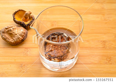 Dried shiitake mushrooms, a measuring cup, and water 133167551