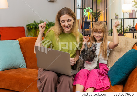 Mother daughter dog win game on laptop get positive test result celebrate good news smile together Mother daughter dog win game on laptop get positive test result celebrate good news smile together 133167660