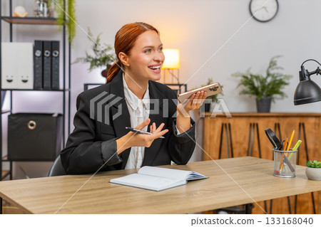 Young businesswoman talking on smartphone call with client writing notes seals big business deal Young businesswoman talking on smartphone call with client writing notes seals big business deal 133168040
