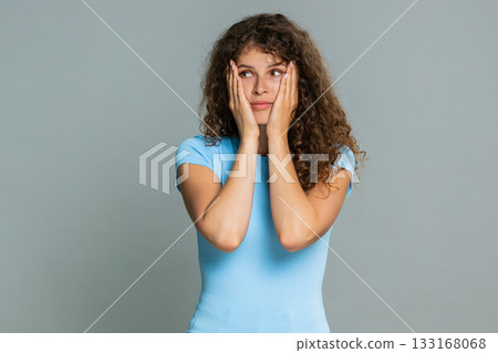 Young woman covering face with hands feeling embarrassed shy ashamed awkward emotional reaction Young woman covering face with hands feeling embarrassed shy ashamed awkward emotional reaction 133168068