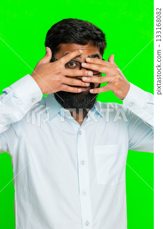 Indian man covering one eye with hand in spy gesture showing intrigue mystery secret peek chroma key Indian man covering one eye with hand in spy gesture showing intrigue mystery secret peek chroma key 133168082