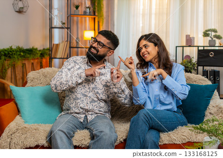 Indian happy family couple man woman dancing together at home, smiling, laughing moving joyfully Indian happy family couple man woman dancing together at home, smiling, laughing moving joyfully 133168125