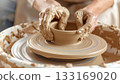 Muddy hands shaping clay on a potters wheel 133169020