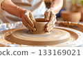 Potter shapes wet clay on wheel 133169021